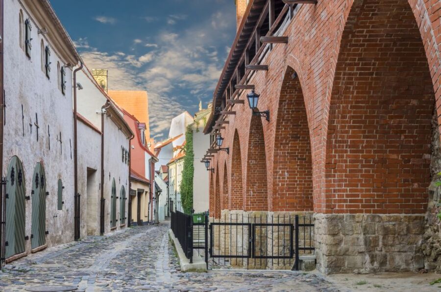 Cobbled street in Riga's old town, featuring historic brick buildings with arched walkways. A glimpse of the city's charming medieval architecture.