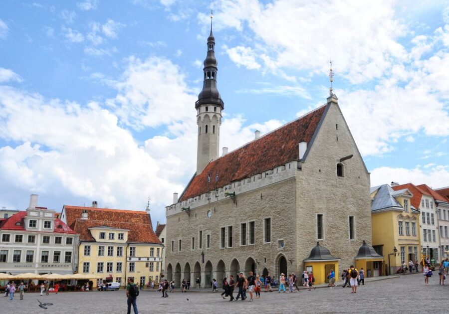 Tallinn Town Hall, a historic building with a tall spire, in the heart of Tallinn's Old Town. People walking in the square.