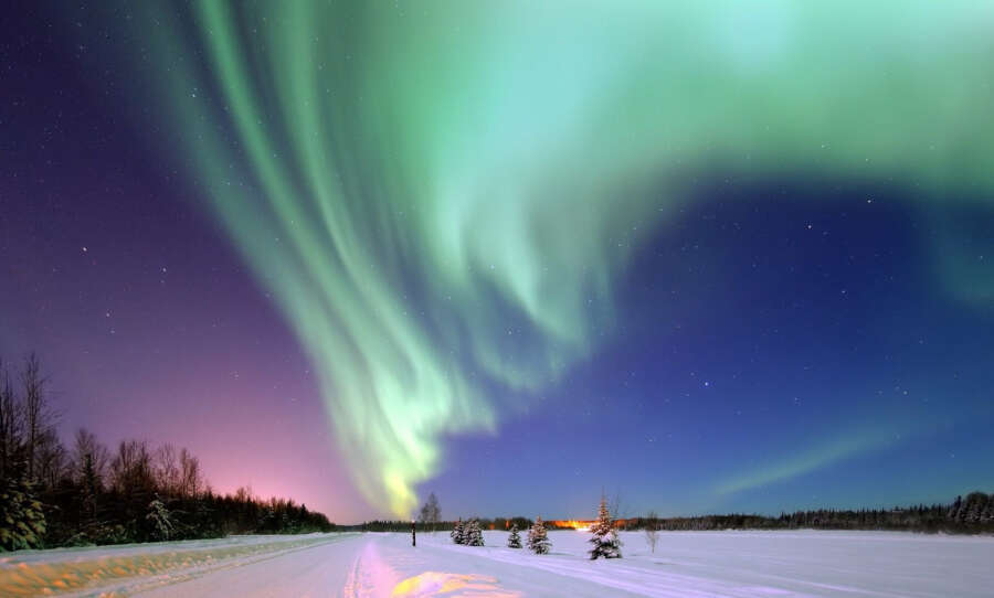 The Northern Lights (Aurora Borealis) over a snowy landscape.