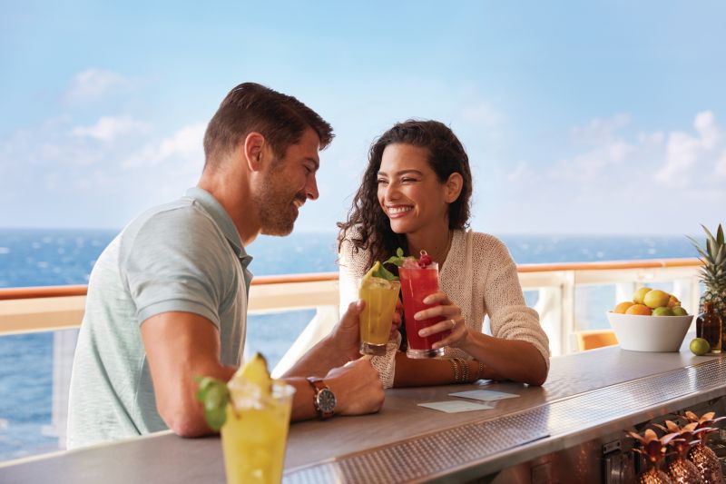 Guests enjoying refreshing mojitos at the Sugarcane Mojito Bar on the NCL cruise ship, with a vibrant and tropical atmosphere.