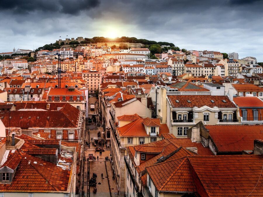 Scenic view of Lisbon's rooftops with colourful buildings and the Tagus River in the background.