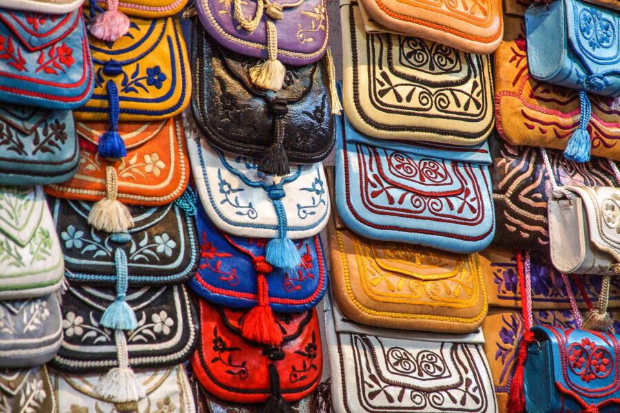 Morocco Guided Tour. Image shows handbags hanging on a wallin a souk