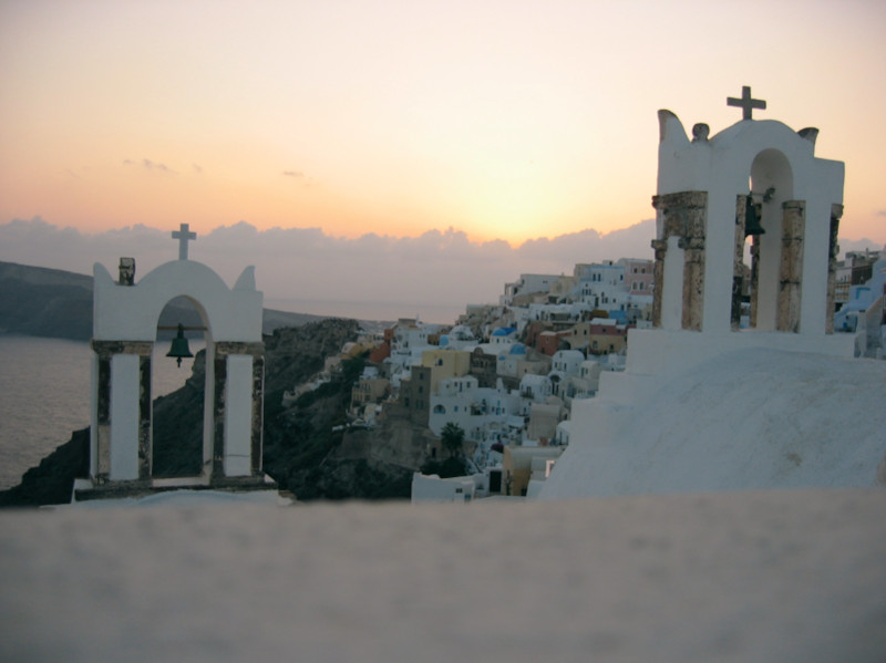 A stunning cityscape of Santorini, Greece, with whitewashed buildings and blue domes cascading down cliffs towards the Aegean Sea.