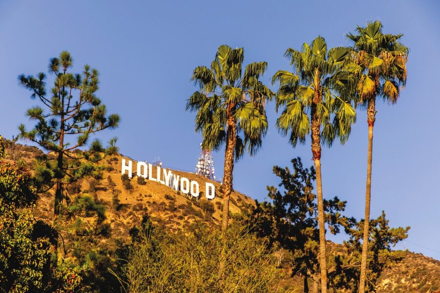 The iconic Hollywood sign in Los Angeles, California, set against a clear blue sky and green hills.