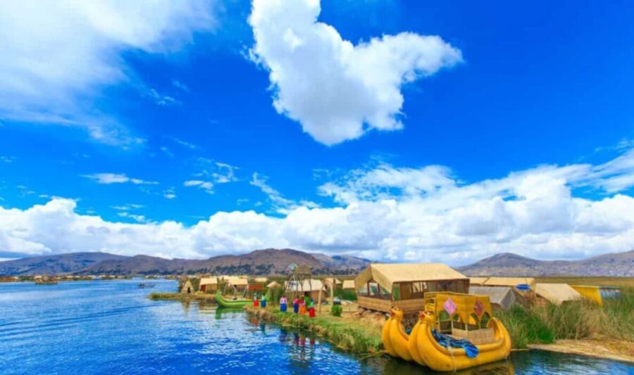 Uros Floating Islands, Lake Titicaca, Peru. Reed islands with houses, people in traditional dress, boats, blue sky, mountains.