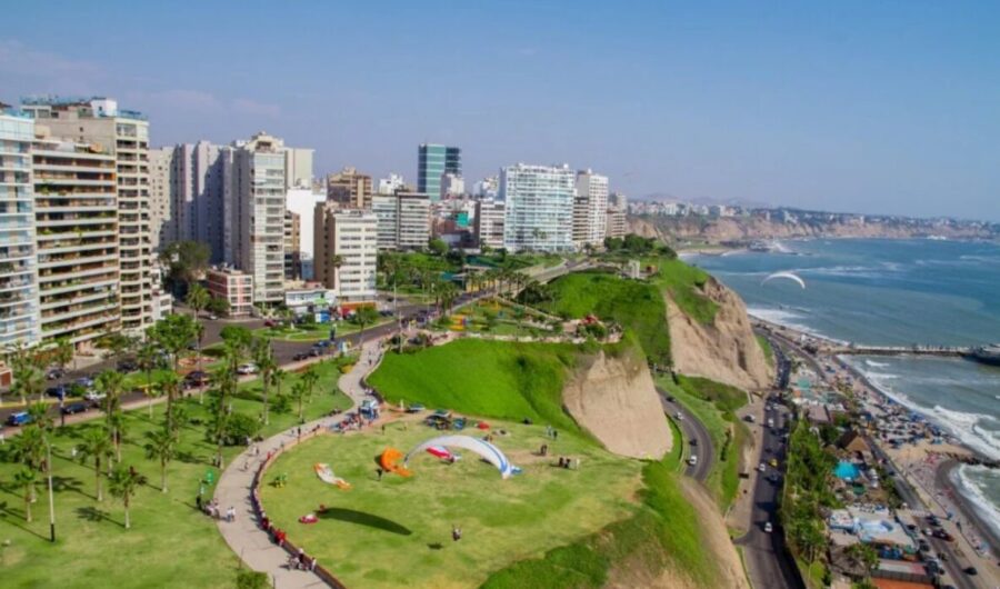 Miraflores, Lima, Peru. Coastal cityscape, modern buildings, paragliders on green clifftop park overlooking ocean.