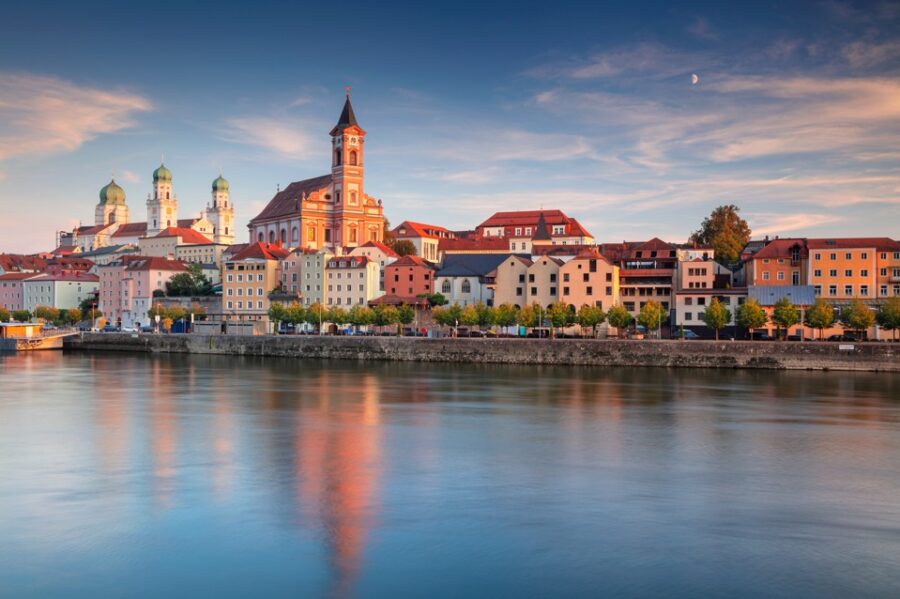 Passau cityscape reflected in river. Bavarian town with church steeple and colourful buildings. River reflection at sunset or sunrise.