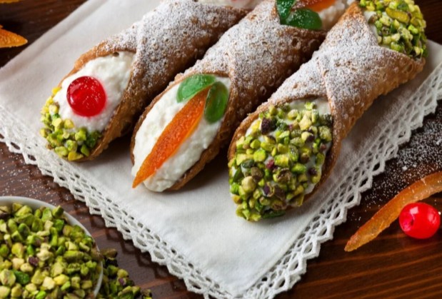 Taste authentic Sicilian cannoli! Crispy pastries bursting with sweet ricotta, dusted with icing sugar, and topped with vibrant pistachios & candied fruit. Pure Italian delight.